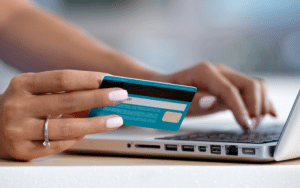 Une femme sur son ordinateur avec sa carte bancaire à la main