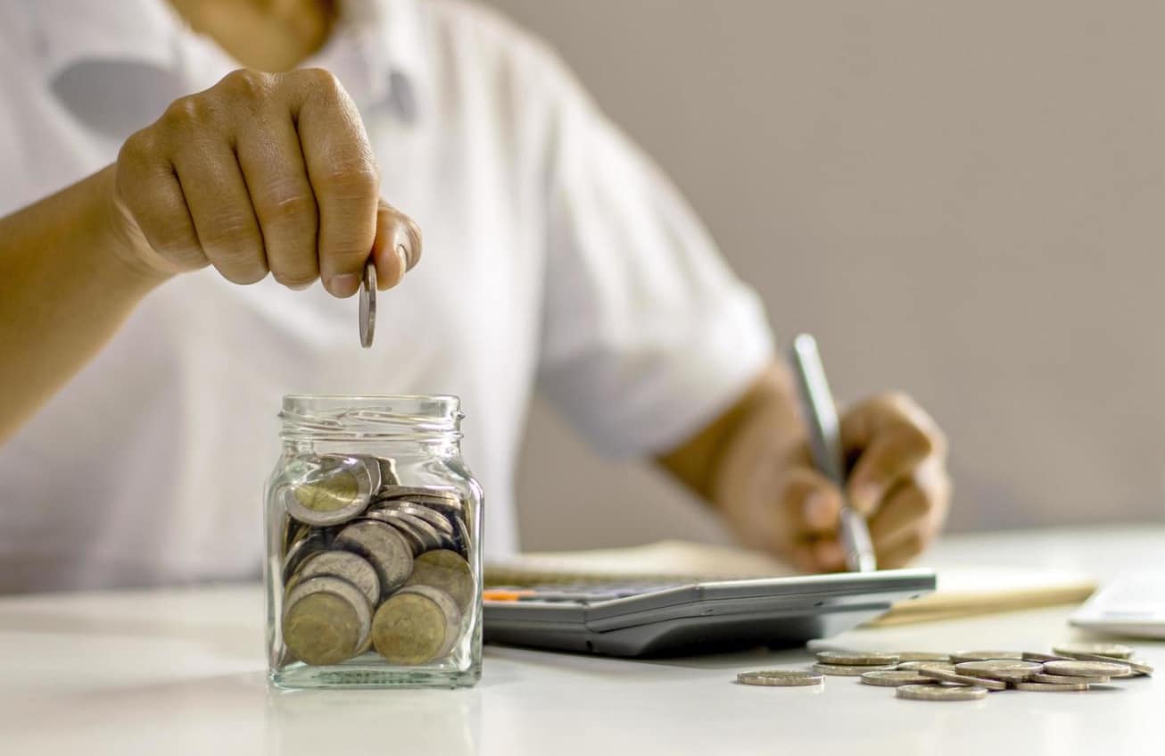 prêt étudiant : étudiant souriant tenant des livres et un ordinateur portable