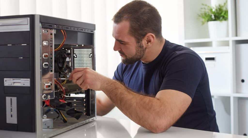 Homme qui répare son ordinateur victime de l'obsolescence programmée